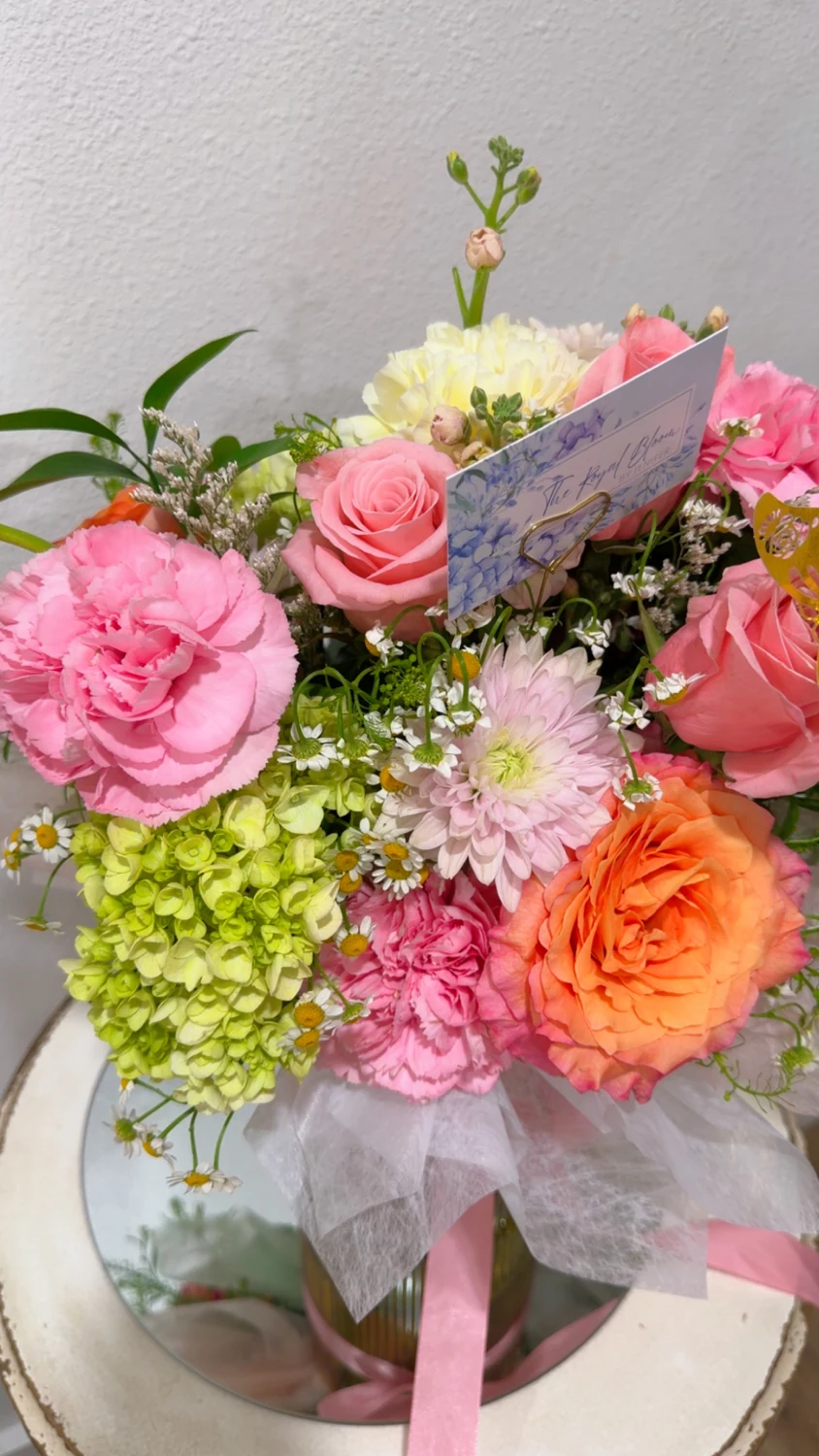 Pink, coral, and pastel flowers arranged in a glass vase